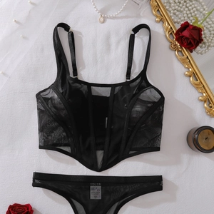 Détail d'un ensemble corset et string en maille noire sur fond élégant avec des roses