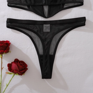 Vue à plat de lingerie en résille noire transparente avec string et roses rouges décoratives