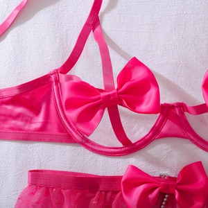 Dettaglio di un set lingerie in pizzo rosa acceso con grande fiocco in raso e cut-out