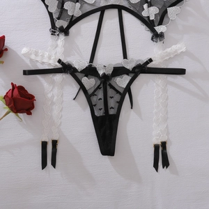 Detail der weißen Herzstickerei auf dem schwarzen Mesh-Strumpfgürtel und Thong-Set