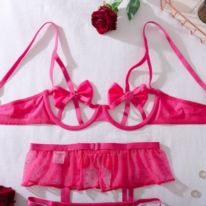 Dettaglio del set di lingerie rosa acceso con grandi fiocchi di seta e volant in rete