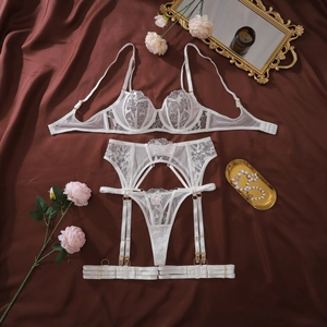 Detailed view of white floral lace lingerie set with garters on dark satin background