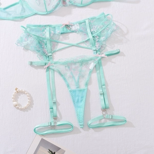 Close-up of floral embroidery and light pink ribbon bows on mint green lace lingerie
