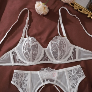 Close-up of white floral lace lingerie set with mesh fabric on dark silk background
