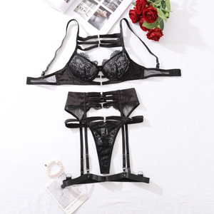 Flat lay of black lace lingerie set with mesh details and red roses on white background