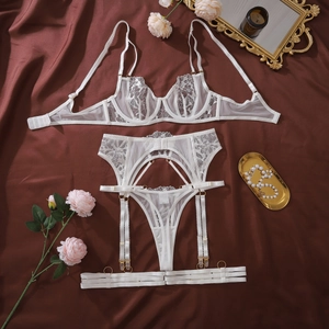 Detailed flat lay of white floral lace lingerie set with mesh fabric and gold hardware