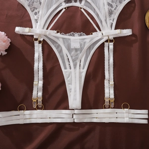 Detail of white lace lingerie set with floral embroidery and golden metal ring hardware