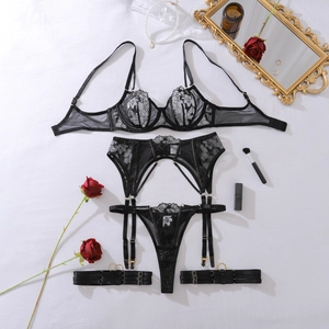 Flat lay of a black sheer lace lingerie set with floral embroidery and garter details