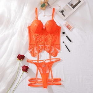 Flat lay of bright orange lace lingerie set with floral embroidery on white sheets