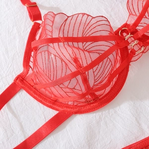 Détail d'un soutien-gorge en dentelle rouge avec broderie dorée et anneaux en métal