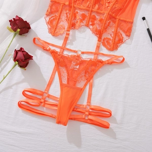 Detail of bright orange floral lace lingerie set with garters on white fabric background