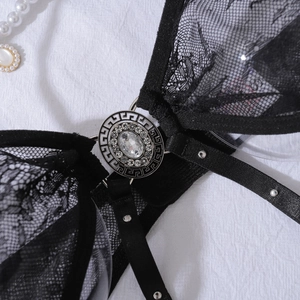 Détail de lingerie en dentelle noire avec médaillon argenté et motif grec méandre