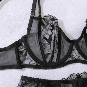 Close-up of black sheer lace lingerie with floral embroidery and golden metal adjusters