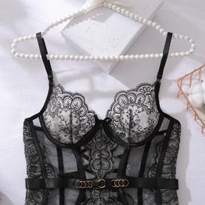 Détail d'un body en dentelle florale noire avec anneaux dorés et broderie pure
