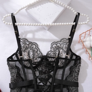 Détail d'un caraco en dentelle noire avec broderie florale et laçage croisé au dos