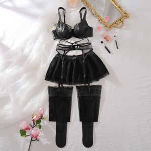Detail eines schwarzen Spitzen-Lingerie-Sets mit Satin-BH, Strapsrock und Strümpfen