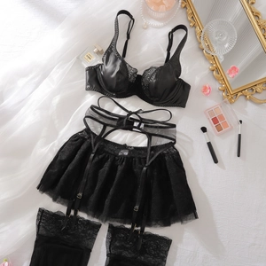 Flachbild von schwarzem Spitzen-Lingerie-Set mit Kunstleder-BH und Strümpfen in edler Kulisse
