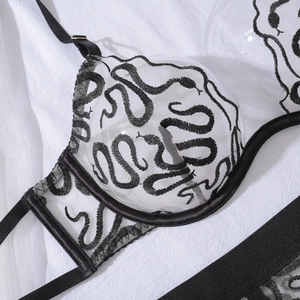 Detail of white mesh bra with black snake embroidery and adjustable straps
