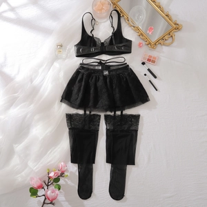 Flachbild von schwarzem Spitzen-Lingerie-Set mit Strapsen und Strümpfen auf weißem Grund
