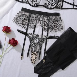 Detail of black lace lingerie set featuring snake embroidery and mesh fabric textures