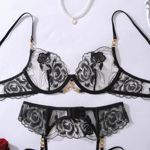 Détail de broderie florale sur lingerie en dentelle noire avec anneaux dorés et rose