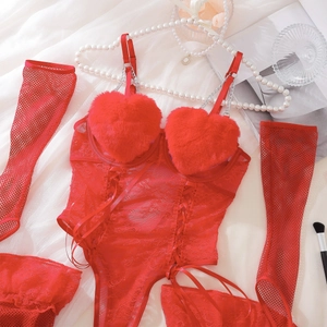 Detail von rotem Spitzen-Bodysuit mit Plüsch-Herzen und Goldketten auf Seidenhintergrund