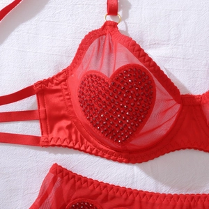 Détail d'un ensemble de lingerie en résille rouge avec cœurs en strass et anneaux dorés