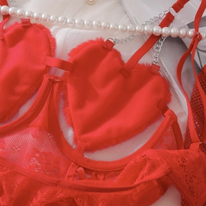 Detail von roter Spitzenunterwäsche mit Plüschherzen und eleganten Silberkettenträgern