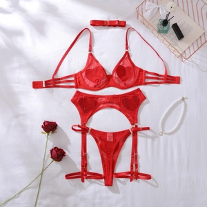 Détail d'un ensemble de lingerie rouge en tulle avec paillettes cœur sur drap blanc