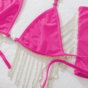 Détail d'un haut de bikini fuchsia avec franges en strass argentés et bordure dentelle