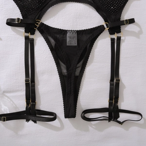 Détail de string en maille noire et porte-jarretelles avec strass et boucles dorées