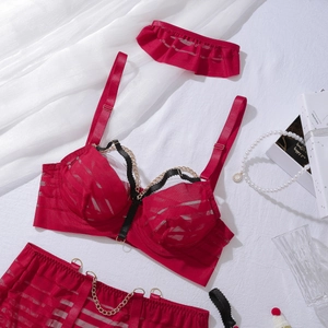 Détail d'un ensemble de lingerie en résille rouge avec chaînes dorées et tissu rayé