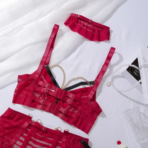 Détail de lingerie en résille rouge avec chaînes dorées sur fond de soie blanche