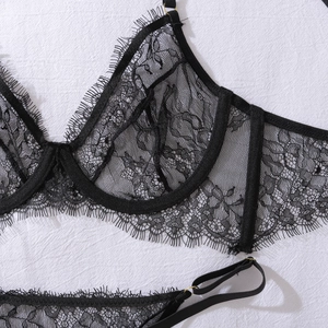 Detail of sheer floral eyelash lace and gold ring hardware on a black underwire bra