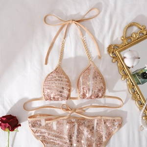 Detail eines Pailletten-Bikini-Sets mit Metallketten auf strukturiertem champagnerfarbenem Stoff