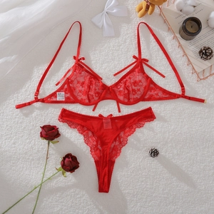 Detailed view of red floral lace lingerie set with bow accents on white plush background