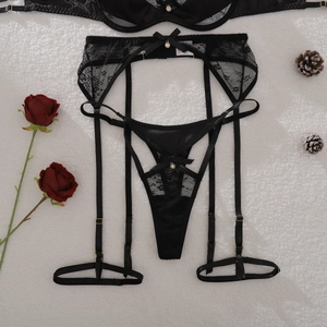 Vue détaillée d'un ensemble porte-jarretelles en dentelle noire avec nœuds en satin chic