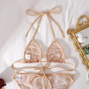 Nahaufnahme des champagnerfarbenen Spitzenbikinis mit Goldketten und Materialetikett