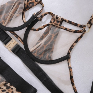 Detailed close-up of leopard print fabric and black mesh with gold metal buckles