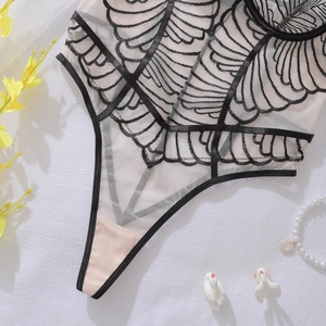 Detailed macro shot of geometric embroidery on a mesh bodysuit with satin edging