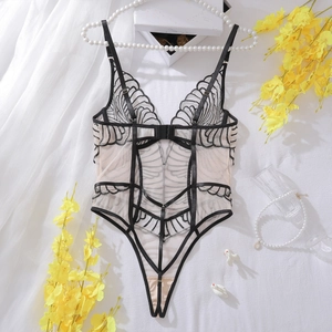Close-up of geometric lace embroidery on a mesh bodysuit with floral and pearl accents