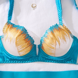Detailed close-up of blue lace bra featuring gold feather embroidery and underwire support