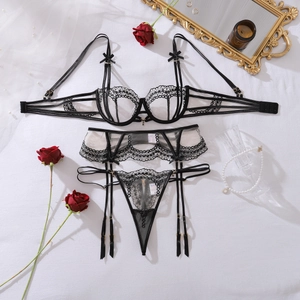 Flat lay of black floral lace lingerie set with bow detail and garter belt on white fabric