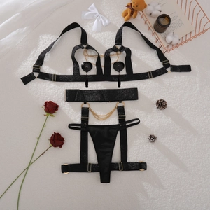 Flat lay of black lingerie set featuring golden chains and heart tassel accents