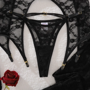 Detailed view of black floral lace lingerie set with gold buckles on plush background