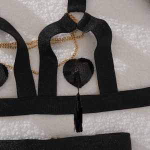 Close-up of black strappy lingerie with gold metal chains and sequin heart tassels