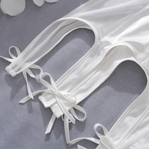 Close-up detail of white satin lingerie with sheer mesh panels and decorative bows