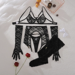 Flat lay of black floral lace lingerie set with garters and long lace gloves on white fur