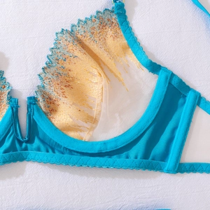 Detailed macro view of blue lace lingerie with gold feather embroidery and steel underwire