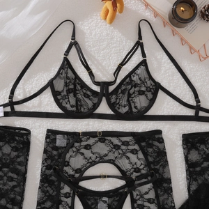 Close-up of black floral lace lingerie set with gold buckles on a white plush rug